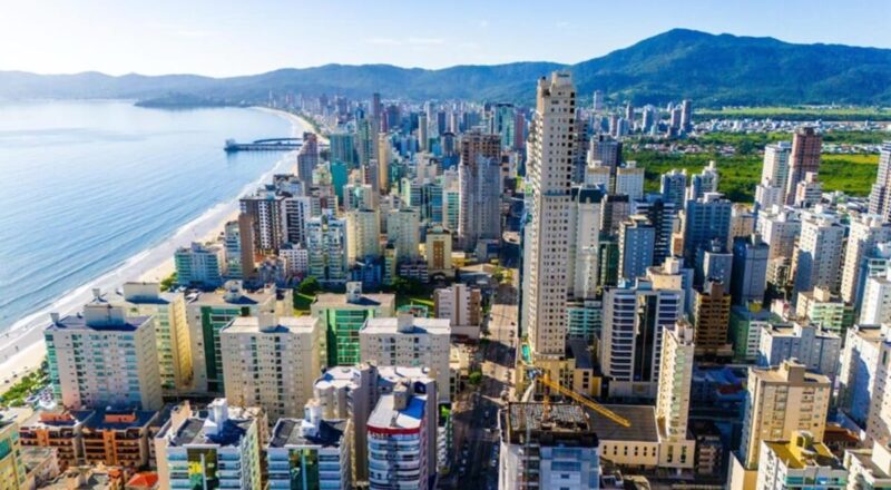 Vista panorâmica da cidade de Itapema, com destaque para construções modernas e o litoral ao fundo.